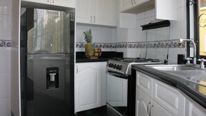 Una cocina con armarios blancos, un refrigerador de acero inoxidable, una estufa y un lavaplatos.