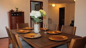 Una mesa de comedor dispuesta con platos, vasos y un florero con flores.
