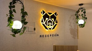 Un área de recepción con un logotipo geométrico y la palabra 'RECEPCIÓN' en la pared.