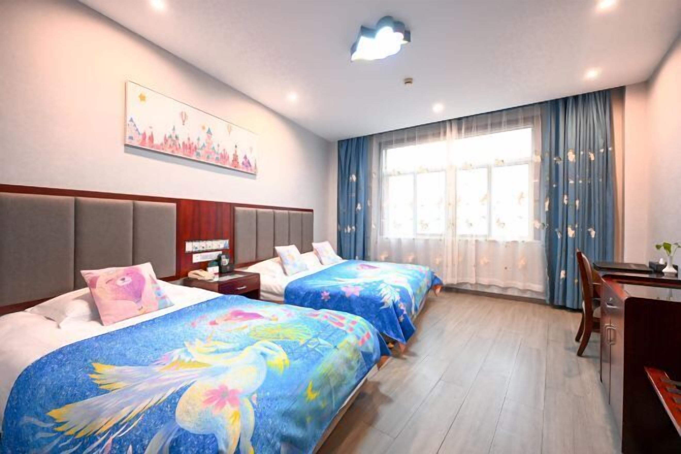 A hotel room with two beds, a desk, a chair, and a large window with curtains.
