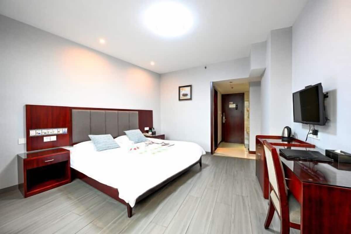Habitación de hotel con cama, mesita de noche, televisor, escritorio y silla.