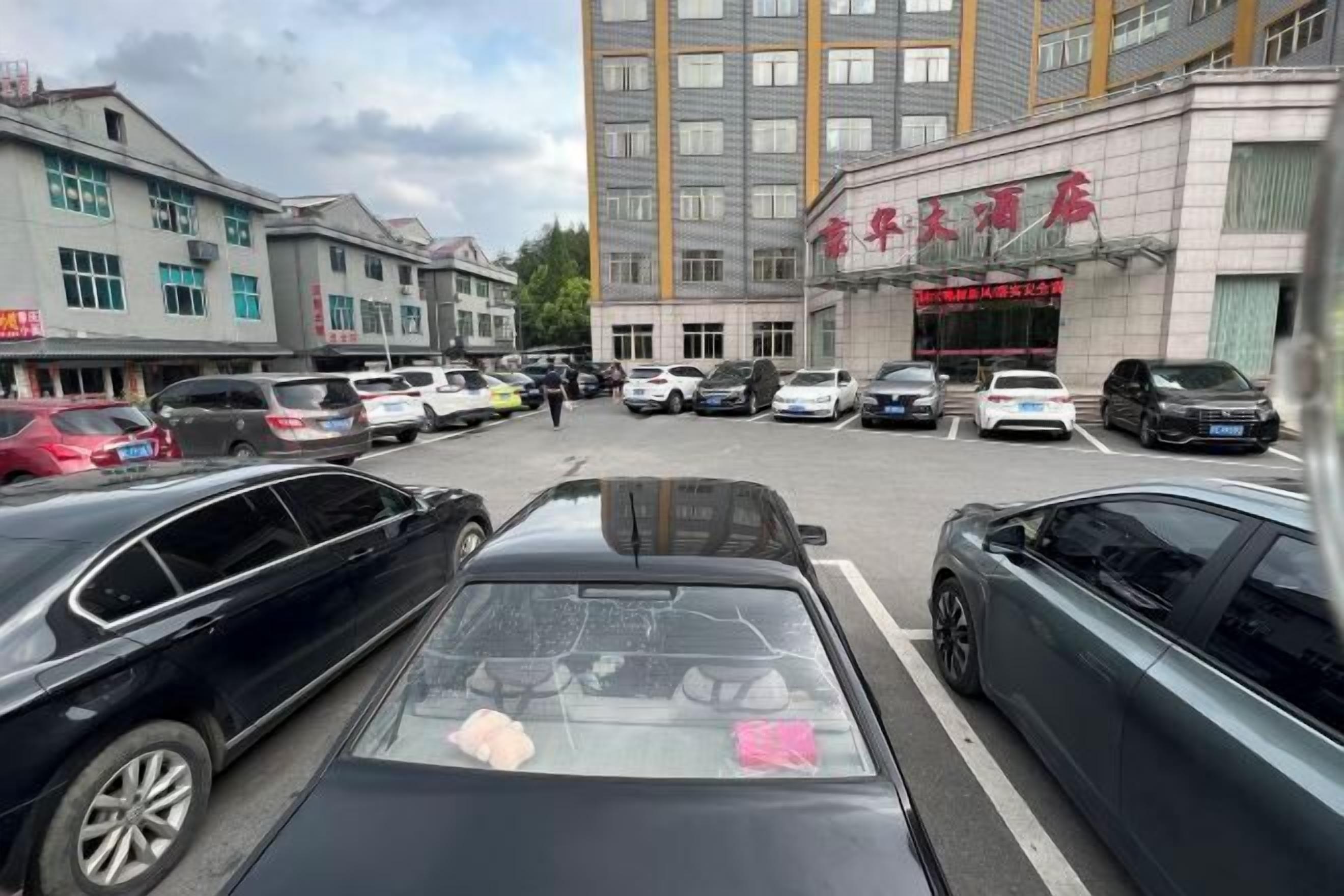 A parking lot with multiple cars and a building with a red sign.