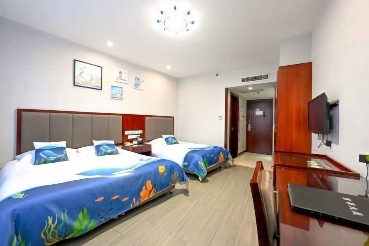 Una habitación de hotel con dos camas, un escritorio, un televisor y obras de arte en la pared.