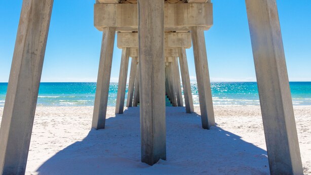 A pier structure with concrete pillars extending over a sandy beach. - Royal Palms Retreat 3 Bedroom Home by RedAwning (Panama City Beach)