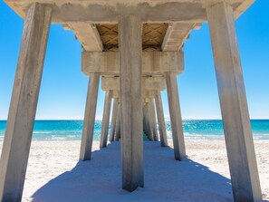 A pier structure with concrete pillars extending over a sandy beach. - Royal Palms Retreat 3 Bedroom Home by RedAwning (Panama City Beach)