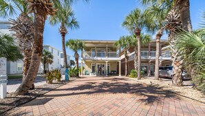 A hotel with a paved entrance, palm trees, and a two-story building with balconies. - Royal Palms Retreat 3 Bedroom Home by RedAwning (Panama City Beach)