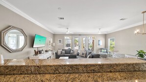 A spacious living area with a large sectional sofa, a flat-screen TV, and a kitchen counter. - Royal Palms Retreat 3 Bedroom Home by RedAwning (Panama City Beach)