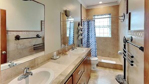 A modern bathroom with two sinks, a toilet, a bathtub, and a shower curtain.