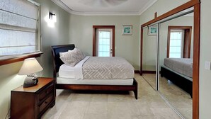A bedroom with a bed, a nightstand, a lamp, a dresser, and a large mirror.