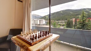 Un tablero de ajedrez sobre una mesa de madera junto a una ventana con vistas a la montaña.