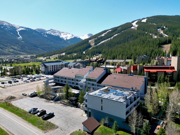 Un hôtel à plusieurs étages doté d’un parking, entouré de montagnes et de forêts.