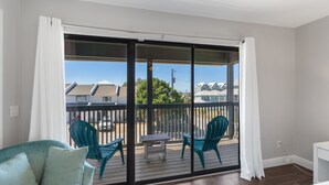 A balcony with a view of houses, a table, and two chairs.