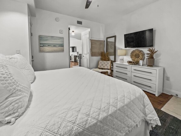 A bedroom with a large bed, a dresser, a television, and a painting on the wall. - Sea La Vie 1 Bedroom Condo by RedAwning (Panama City Beach)