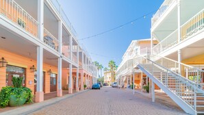 Una calle flanqueada por edificios de varios pisos, con balcones, adoquinado de ladrillo y cielo despejado.