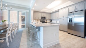 A modern kitchen with a central island, stainless steel appliances, and light-colored cabinetry. - Phoenix Gulf Towers 405 5 Bedroom Condo by RedAwning (Orange Beach)