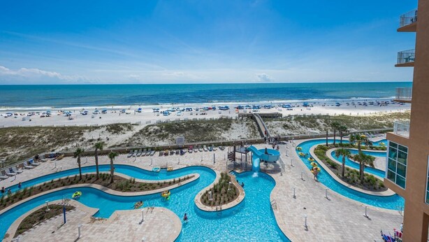 A resort with a large pool area featuring winding water slides and a beach with sun loungers. - Phoenix Gulf Towers 405 5 Bedroom Condo by RedAwning (Orange Beach)