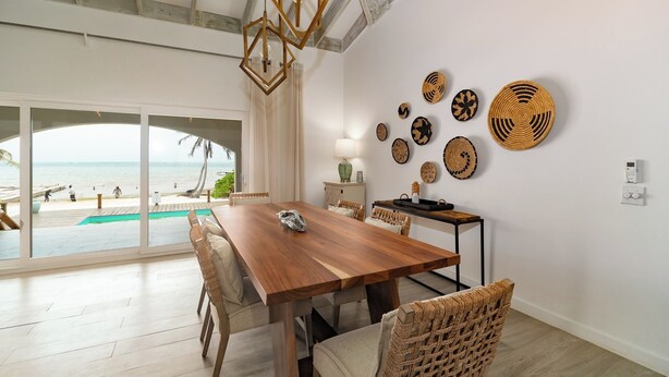 Un grand espace dédié à la salle à manger, avec une table et des chaises en bois, une vue sur la plage et une piscine.