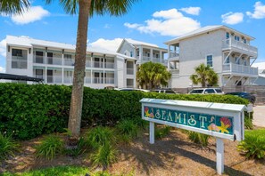 Un hotel frente a la playa con varios balcones, un cartel que dice 'SEAMIST' y abundante vegetación.