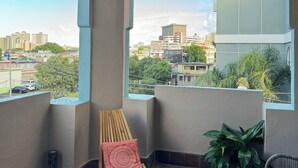 A balcony with a view of the city, a hanging light fixture, a wooden chair with a red cushion, and a potted plant. - NEW cozy & Spacious 5B, 3B, 1 parking close to Condado Beach (San Juan)