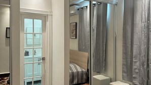 A modern bedroom with a bed, a ceiling fan, a bathroom with a shower curtain, and a patterned floor. - NEW cozy & Spacious 5B, 3B, 1 parking close to Condado Beach (San Juan)