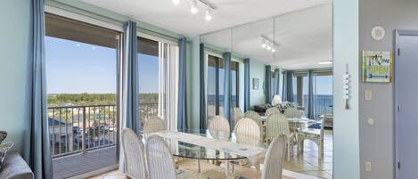 A spacious balcony with a glass table and wicker chairs, overlooking a scenic view.