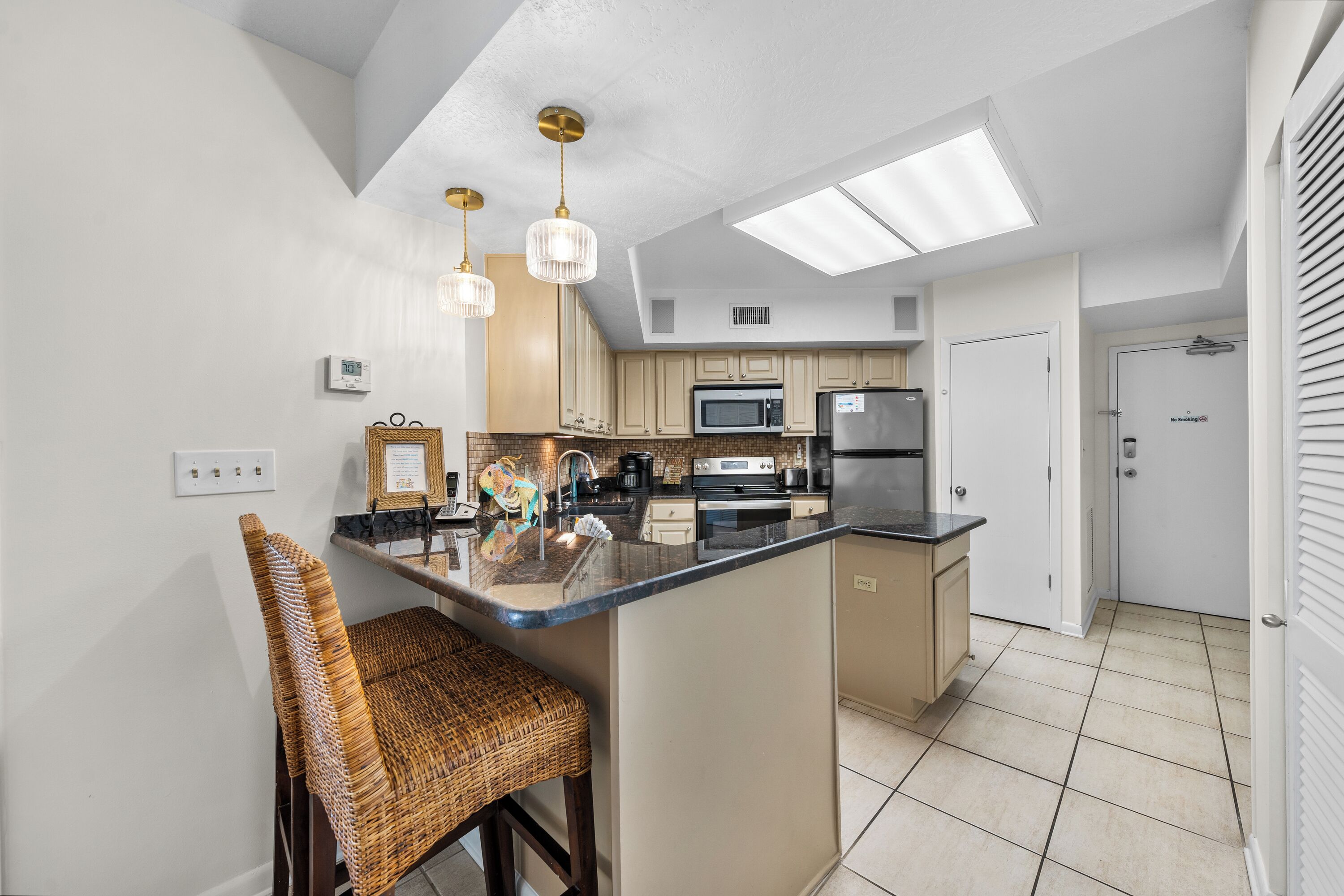 A modern kitchen with a central island, built-in appliances, and pendant lighting.