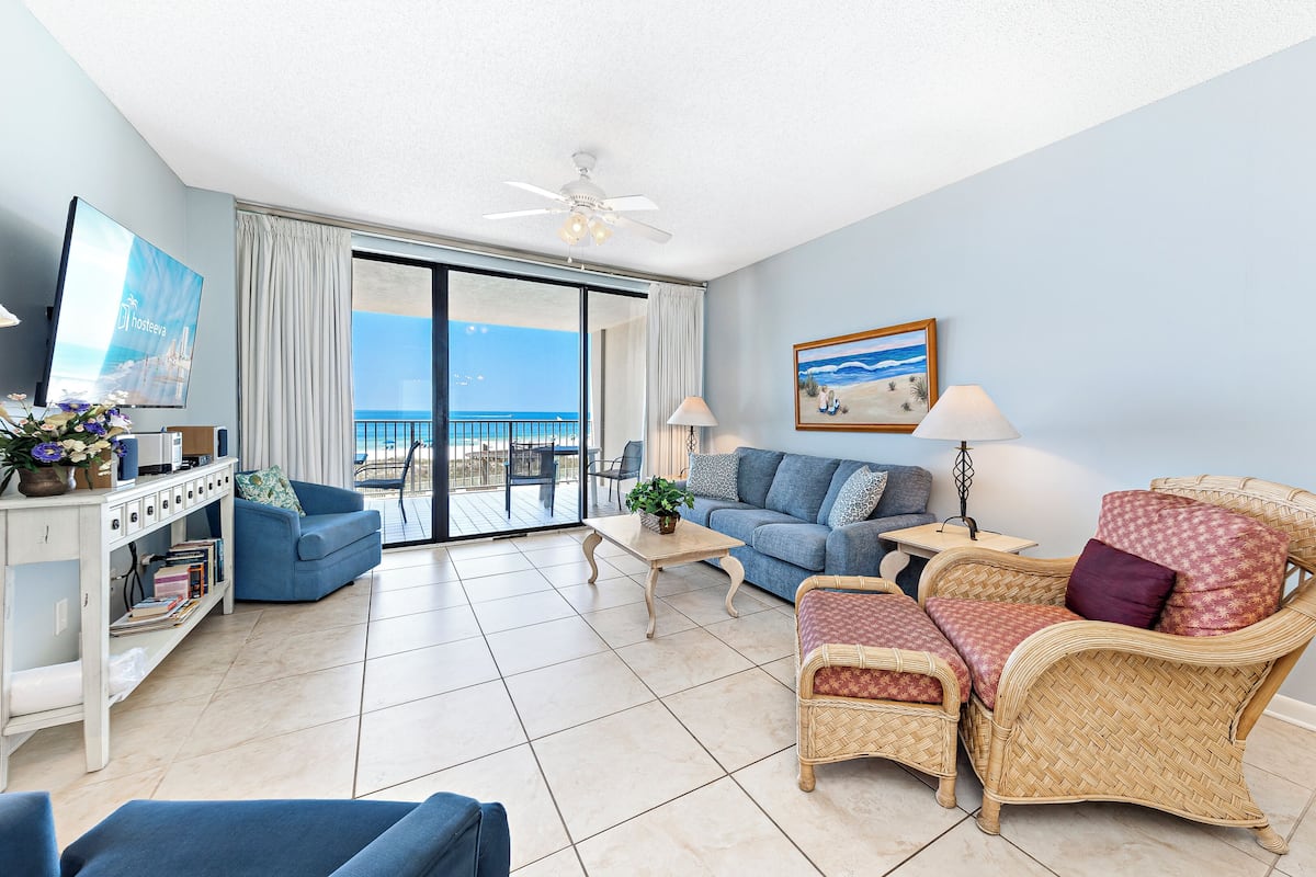 A spacious living room with a balcony, a television, and a comfortable seating area.