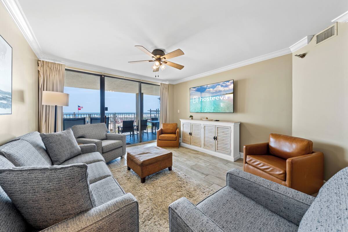 A living room with a sofa set, a brown leather chair, a television, and a ceiling fan.
