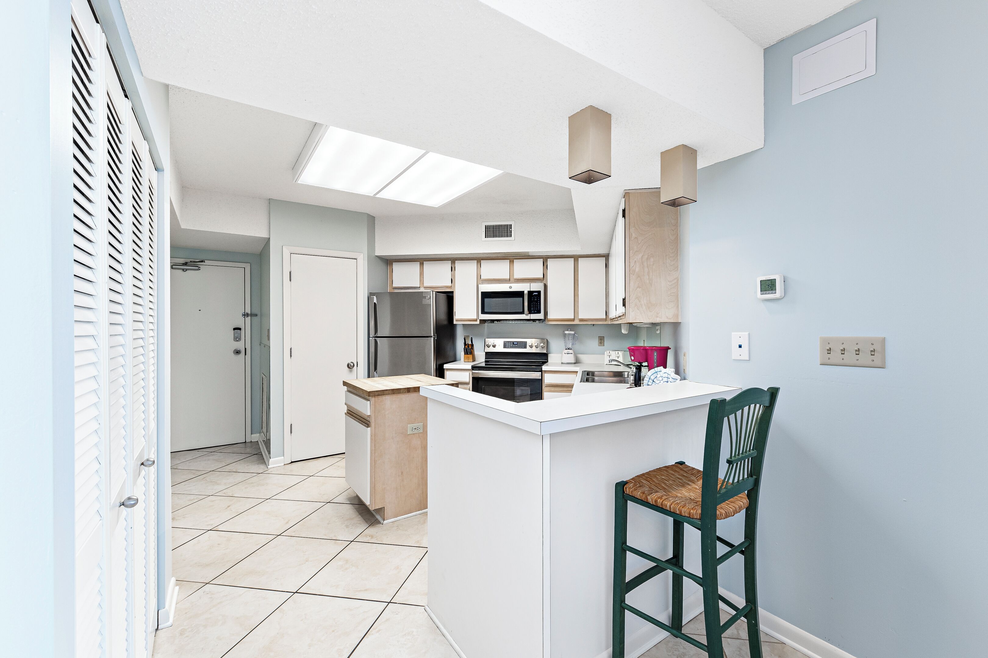 A modern kitchen with a central island, a microwave, and a refrigerator.