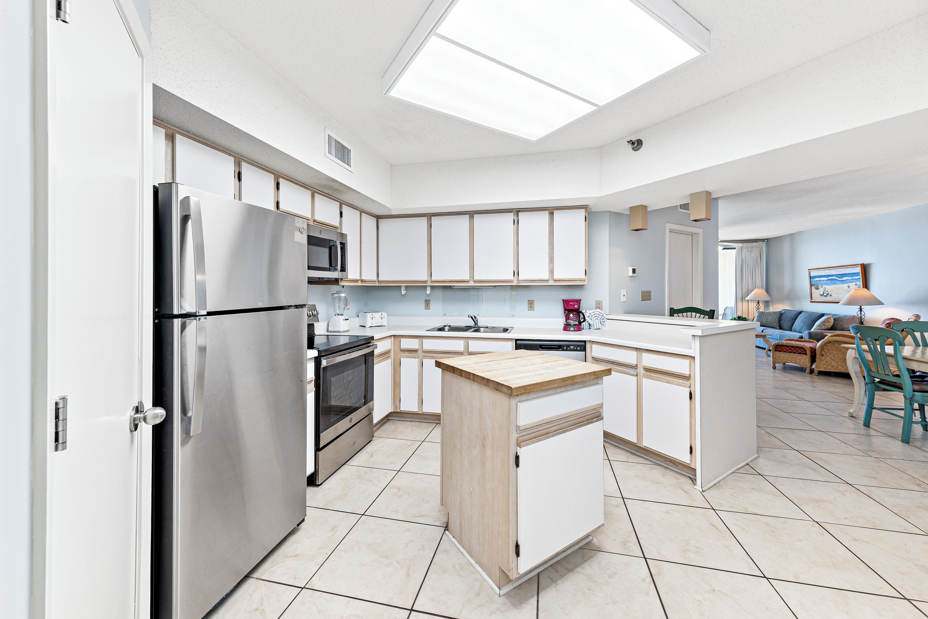 A modern kitchen with a central island, stainless steel appliances, and a dining area with a sofa and chairs.