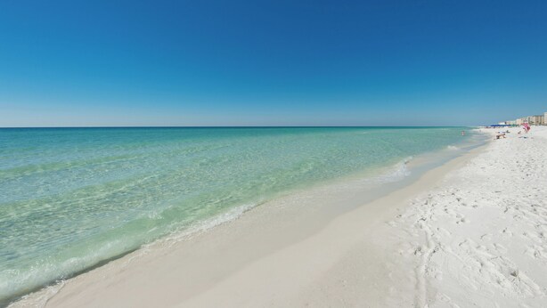 Ein Strand mit klarem türkisblauem Wasser und weißem Sand.