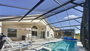 Une piscine extérieure couverte, dotée de chaises longues et d’un espace patio.