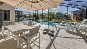 Un espace extérieur abrité comprenant une piscine, des chaises longues et une table.