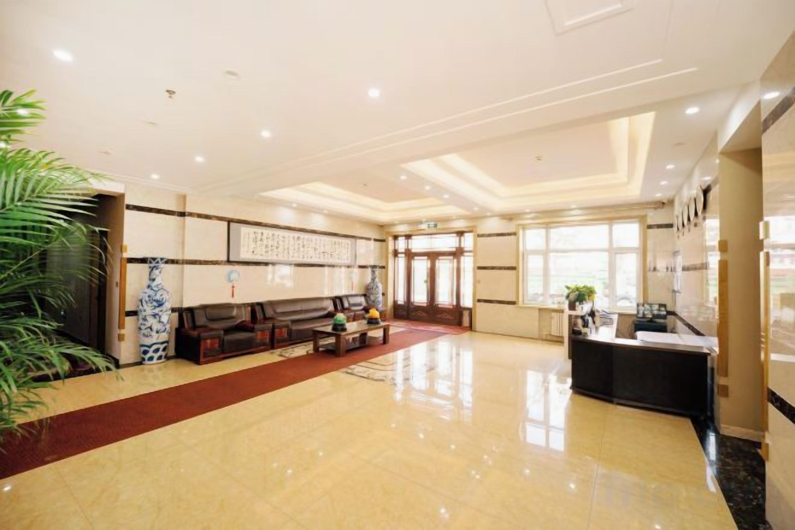 A spacious lobby with a reception desk, seating area, and a large plant.