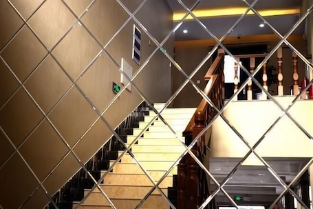 A staircase with a handrail, a sign indicating a direction, and a door at the top.. Shangzhi Longmen Hotel