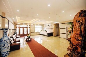 A hotel lobby with a reception desk, seating area, and a decorative vase. - Shangzhi Longmen Hotel (Shangzhi)