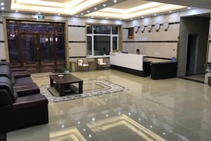 A hotel lobby with a reception desk, seating area, and a large window. - Shangzhi Longmen Hotel (Shangzhi)