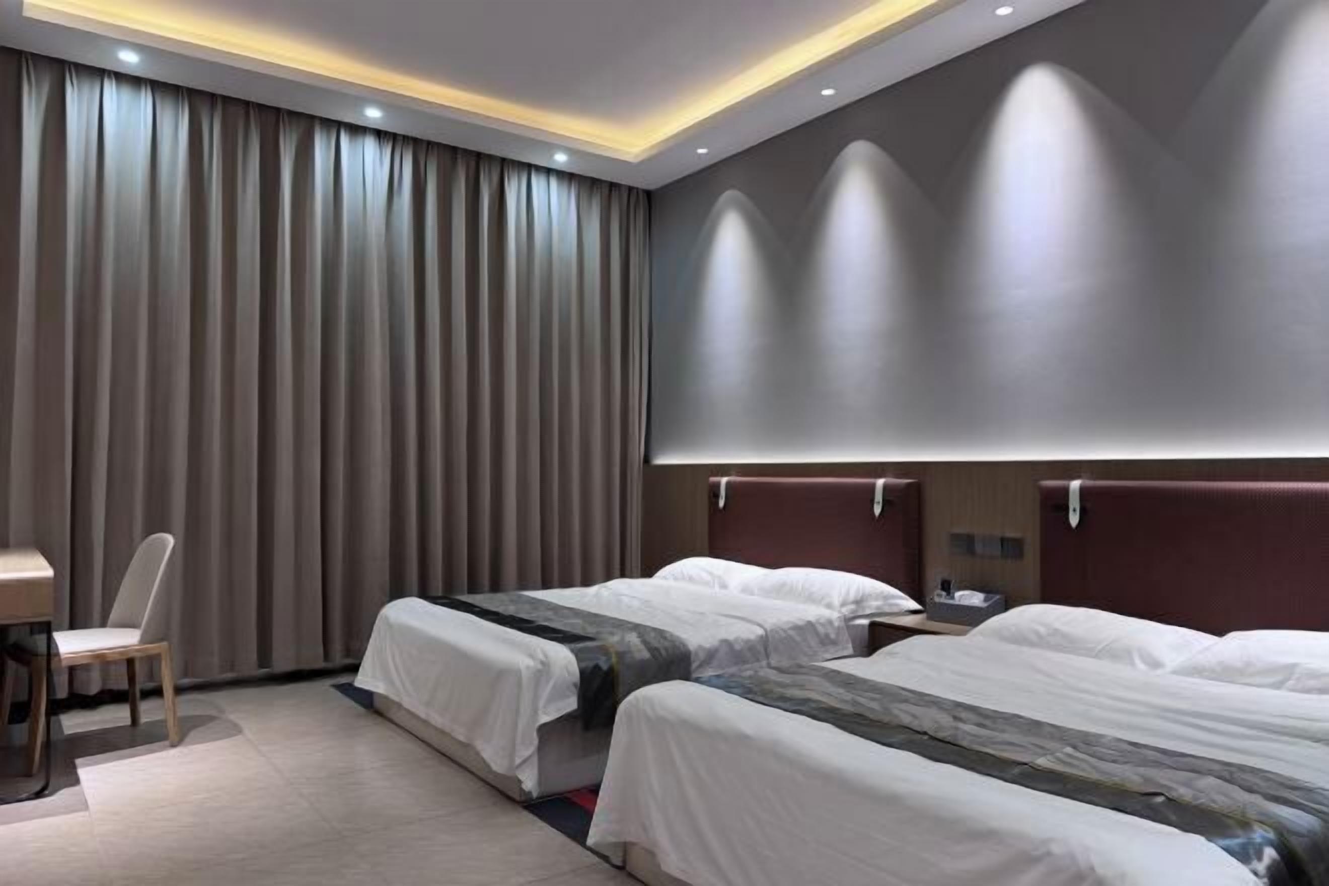 A hotel room with two beds, a desk, a chair, and a large window with curtains.