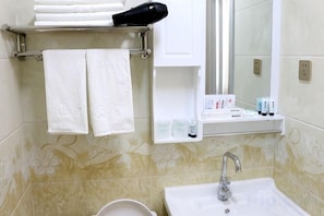 A bathroom with a sink, mirror, towel rack, and toiletries.