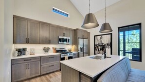 A modern kitchen with dark wood cabinets, stainless steel appliances, and a central island. - Lazy Daze, Black Hills of SD (Sturgis)