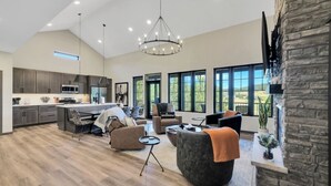 A spacious living area with a kitchen, large windows, and a stone accent wall. - Lazy Daze, Black Hills of SD (Sturgis)