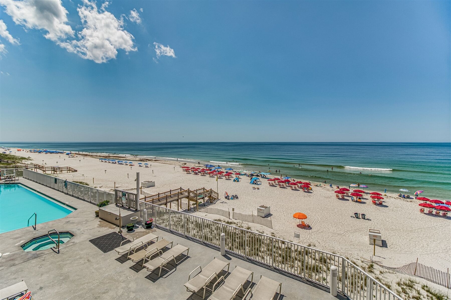 Een strand met een zwembad, ligbedden en parasols.