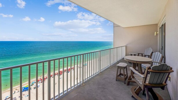 A balcony with a view of the beach and ocean.