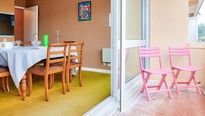 Comedor con una mesa lista para cuatro personas, sillas de madera y un tapete verde.