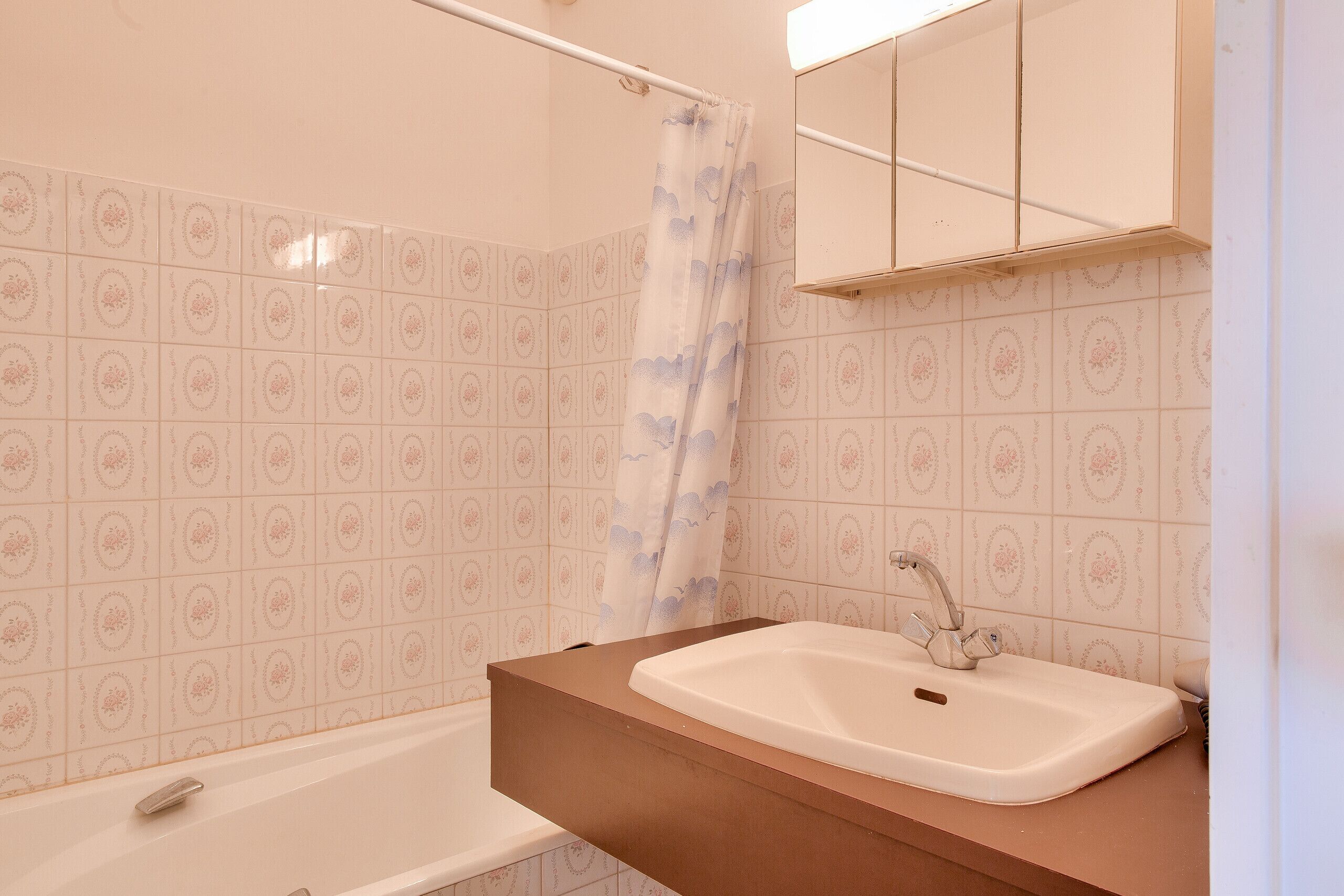 A bathroom with a bathtub, a sink, and a shower curtain.