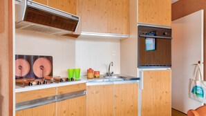 Una cocina compacta con armarios de madera, estufa integrada, un lavamanos y un microondas.