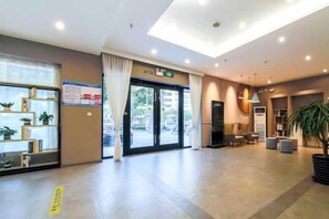 A hotel lobby with a reception desk, seating area, and a large window. - Home Inn (Heyuan Railway Station) (Heyuan)