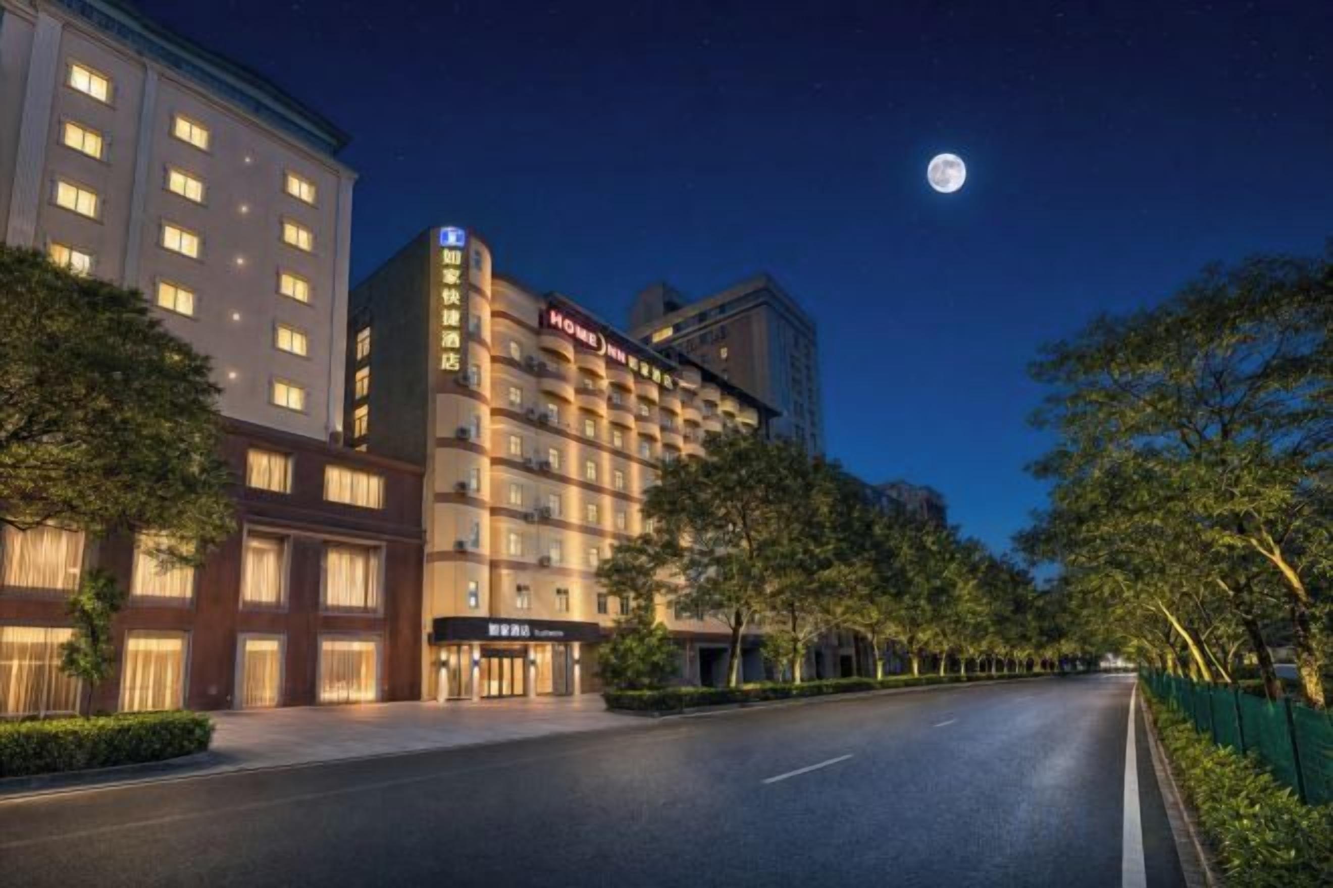 Un hotel con diversi piani, un ingresso ben illuminato e un cielo notturno sereno.