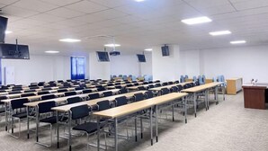 A classroom with rows of desks and chairs, a podium, and ceiling-mounted projectors. - Home Inn (Heyuan Railway Station) (Heyuan)