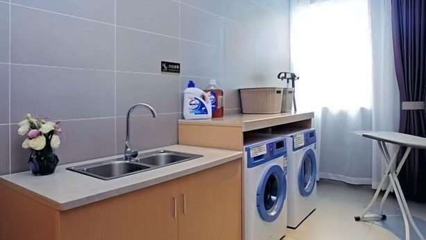 Quarto de hotel compacto com cozinha compacta, máquina de lavar e espaço para passar roupa.